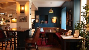 A restaurant interior with wooden furniture, a red carpet, and wall-mounted lighting. - The Jug & Bottle (Wirral)