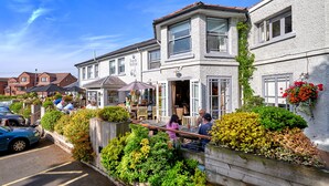 A building with a cafe area, outdoor seating, and a parking lot. - The Jug & Bottle (Wirral)