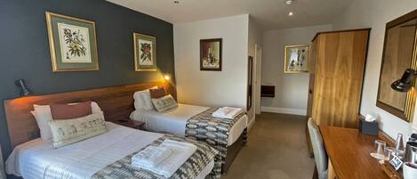 A hotel room with two beds, a wooden dresser, and framed artwork on the walls.