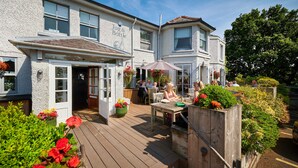 A pub with outdoor seating, a wooden deck, and flower planters. - The Jug & Bottle (Wirral)