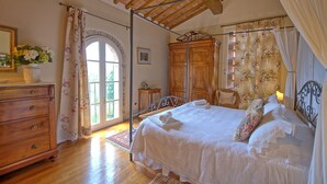 A bedroom with a wooden bed, a dresser, a mirror, and a window with curtains. - Villa Fontine (Castelfranco di Sotto)
