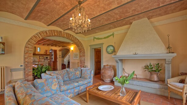 A cozy living room with a patterned sofa, a wooden coffee table, and a fireplace. - Villa Fontine (Castelfranco di Sotto)