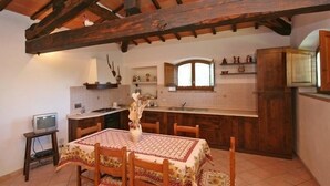 A rustic kitchen with wooden beams, a dining table with chairs, and a television on a stand. - Pienza (Pienza)