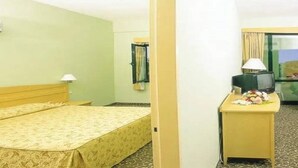 A hotel room with a bed, a desk with a lamp, a television, and a mirror on the wall. - Arinna Hotel (Manavgat)