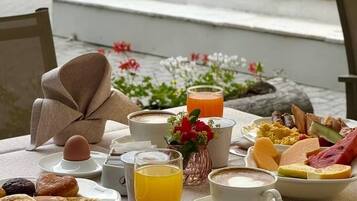 Une table de petit-déjeuner avec divers aliments, une tasse de café et un verre de jus d’orange.
