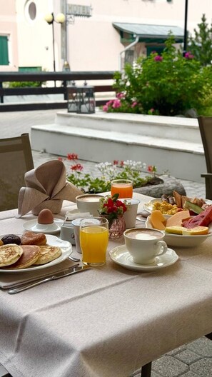 Une table de petit-déjeuner avec divers aliments, une tasse de café et un verre de jus d’orange.