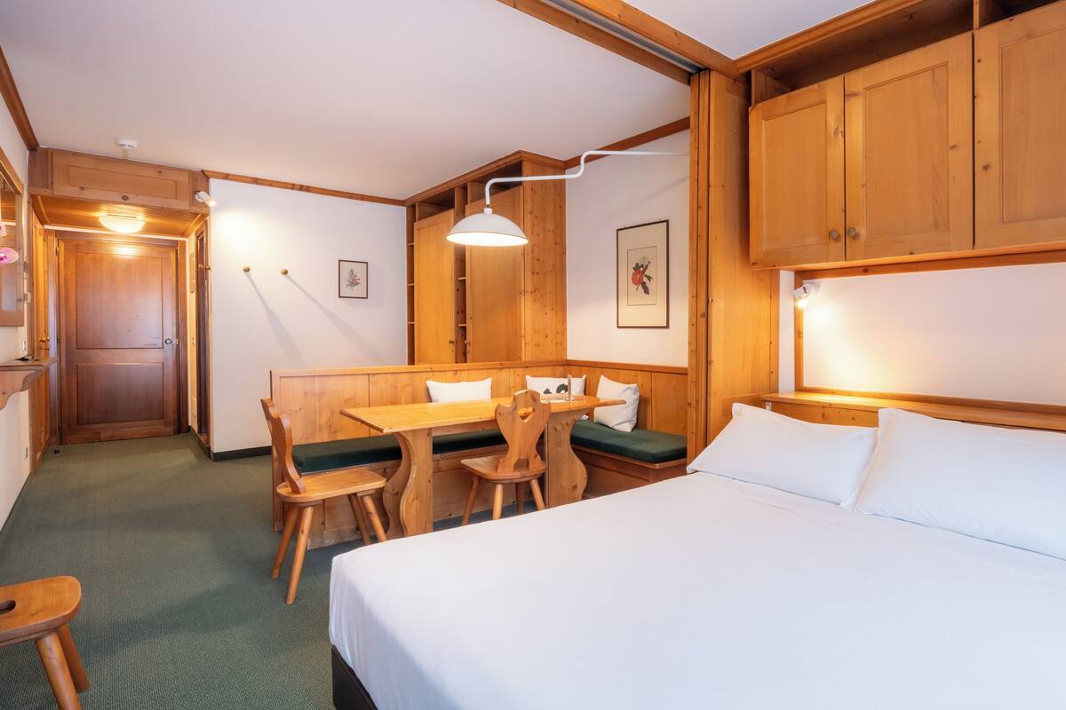 Une pièce comprenant un lit, des meubles en bois, un banc et une table.