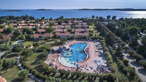 An aerial view of a resort with a large swimming pool surrounded by villas, a beach area, and a view of the sea. - Mobile Homes Adriatic Camping Bi Village (Fazana)