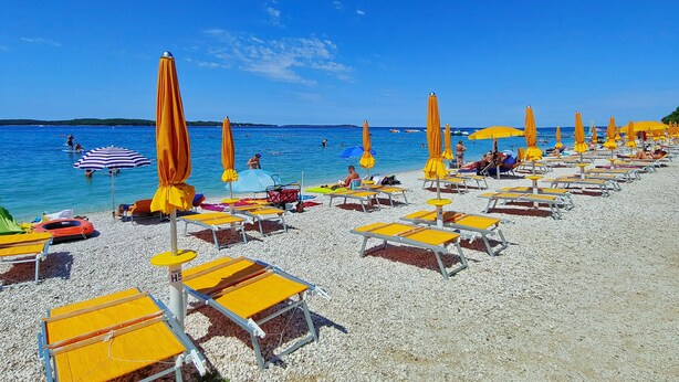 A beach with rows of sun loungers and umbrellas, a clear blue sky, and calm sea. - Mobile Homes Adriatic Camping Bi Village (Fazana)