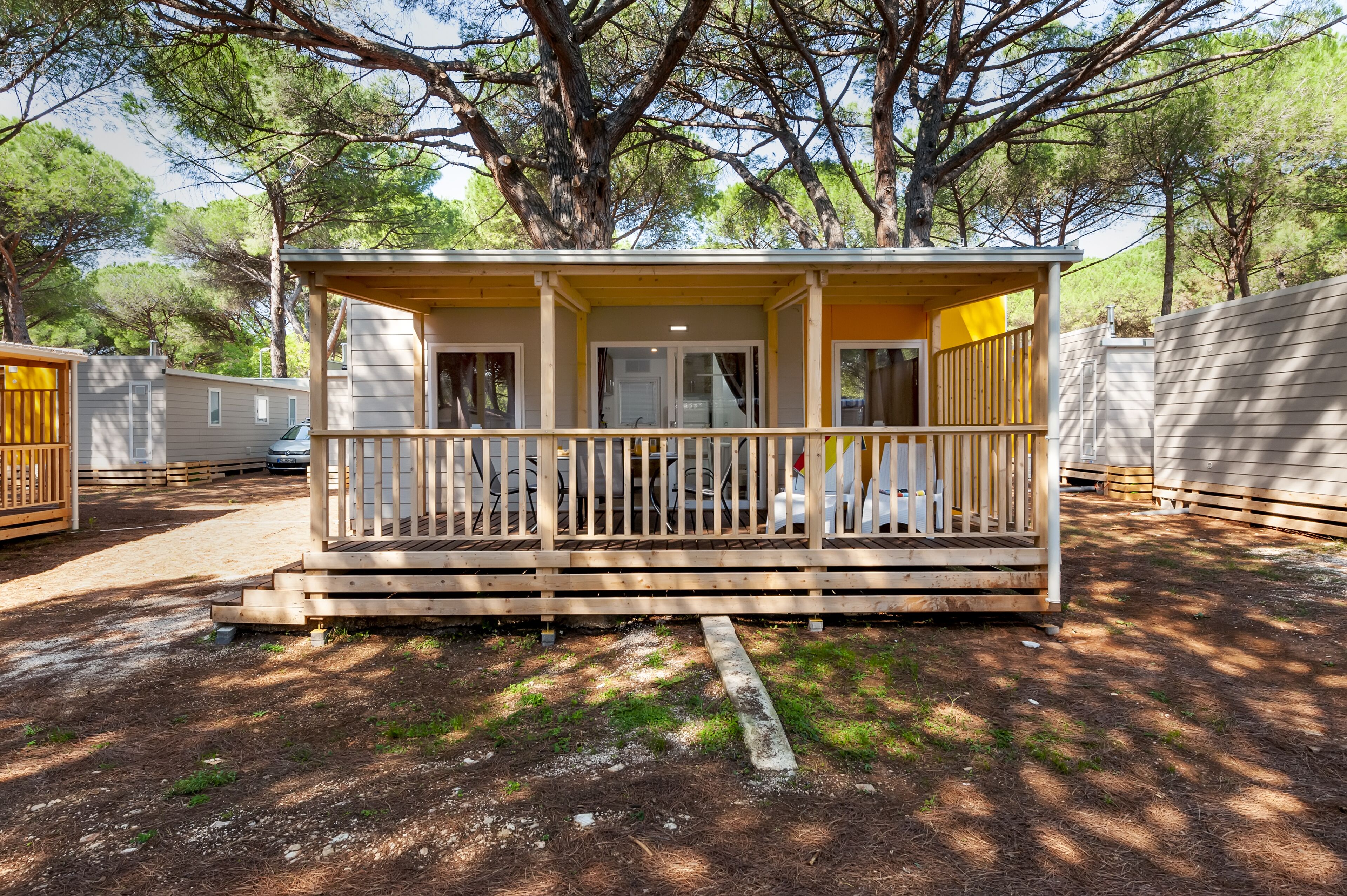 A small wooden cabin with a porch, surrounded by trees.