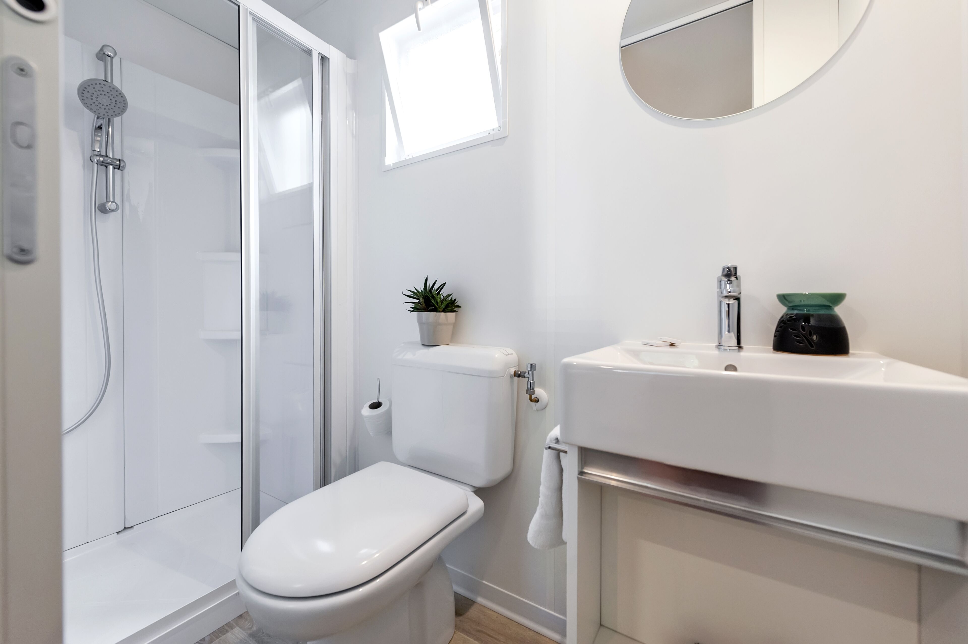 A modern bathroom with a toilet, shower, and sink.