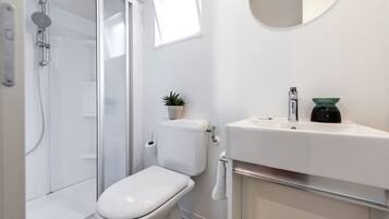 A modern bathroom with a toilet, shower, and sink.