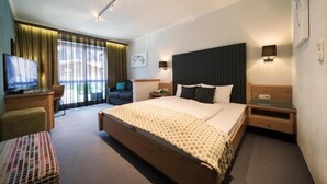 A hotel room with a large bed, a desk with a television, a chair, and a sofa. - Montjola (Sankt Anton am Arlberg)