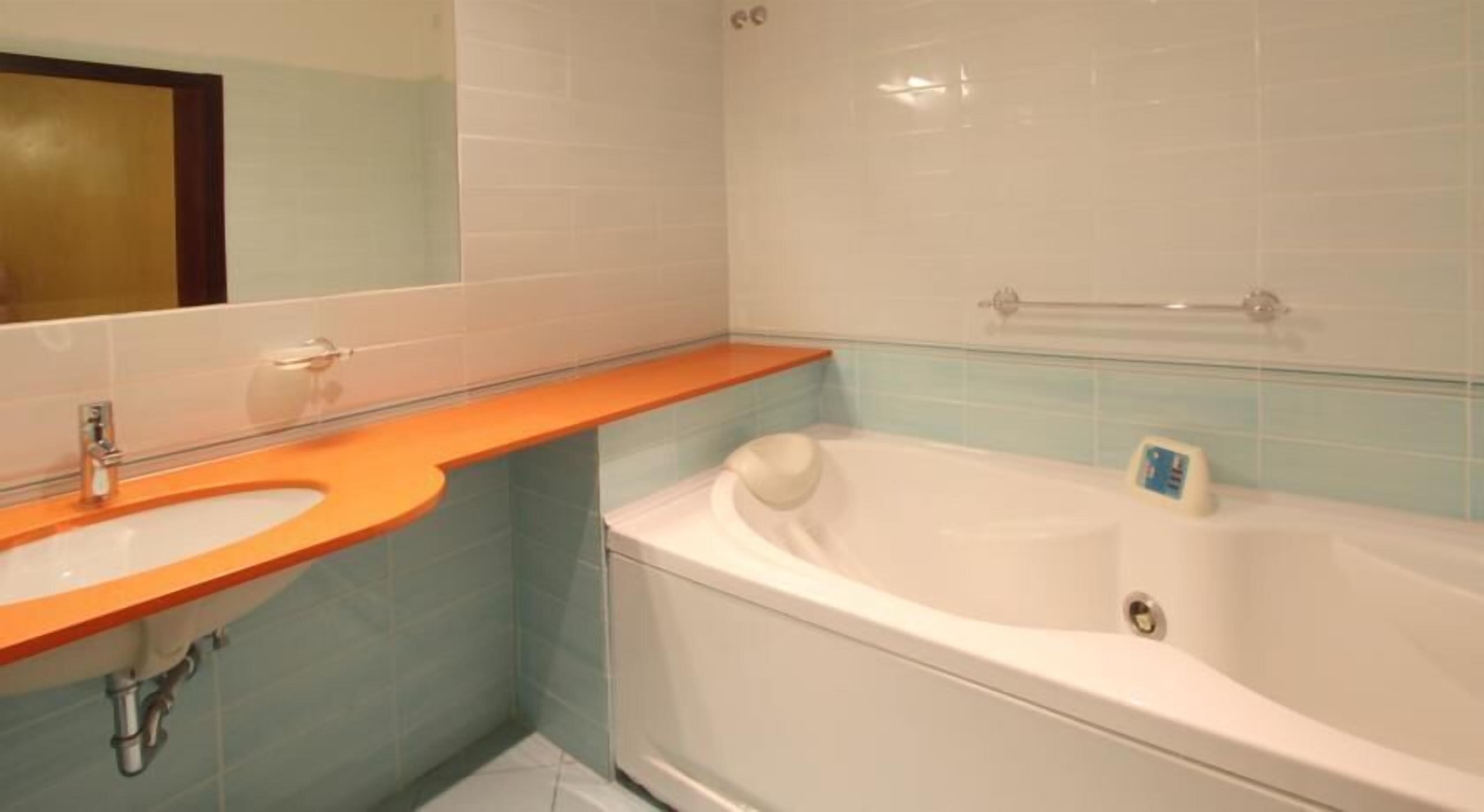Une salle de bain avec un lavabo, un miroir et une baignoire.