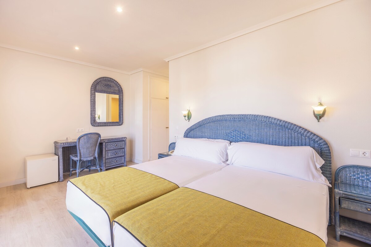 Une chambre d’hôtel avec un grand lit, un bureau et une chaise.