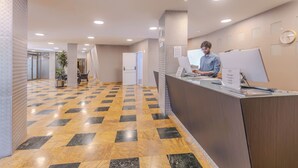Un espace d’accueil comprenant un comptoir d’enregistrement, un(e) réceptionniste et un bureau de réception.