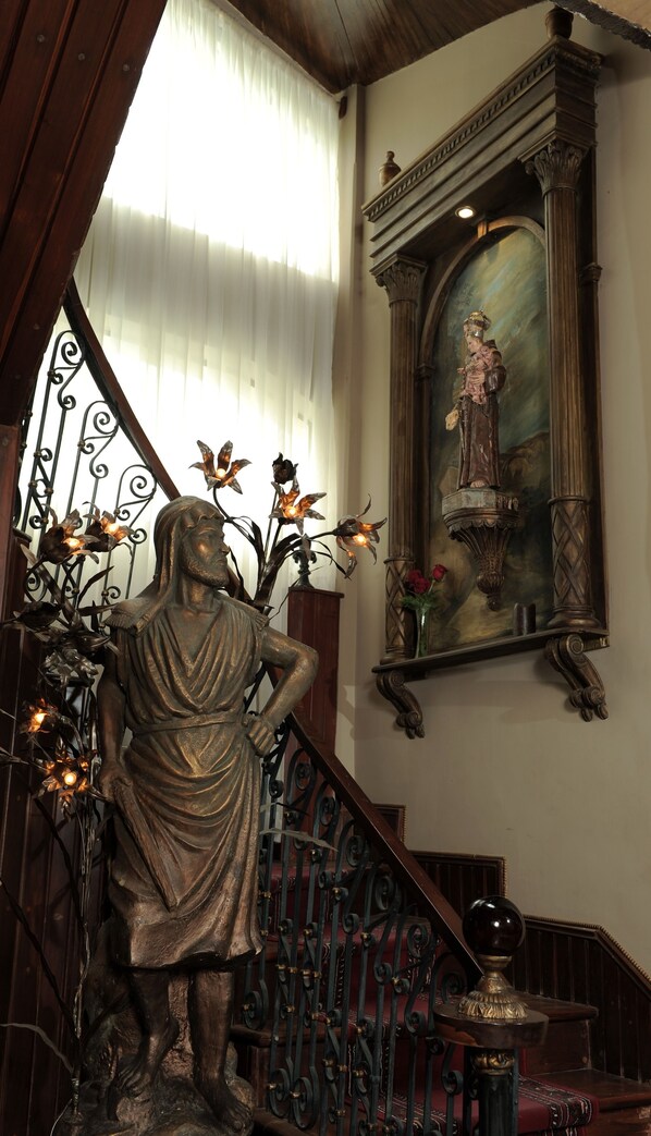 Un escalier orné d’une statue, d’un tableau et d’une rampe en métal décorative.