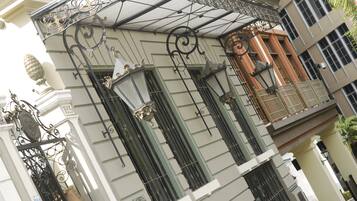Un edificio con barandillas de hierro ornamentadas, un toldo verde y un cartel que indica el año 1906.