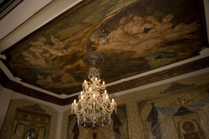A grand chandelier in a room with ornate ceiling artwork and architectural details.