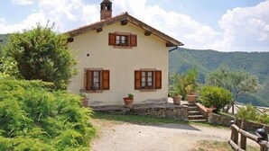 A rustic house with a stone staircase leading to the entrance, surrounded by lush greenery and hills in the background. - Villa Margherita Due (Cortona)