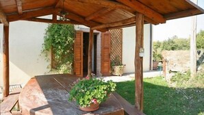 A wooden pergola with a table and potted plants. - Villa Margherita Due (Cortona)
