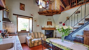A cozy kitchen with a dining area, a fireplace, and a staircase. - Villa Margherita Due (Cortona)