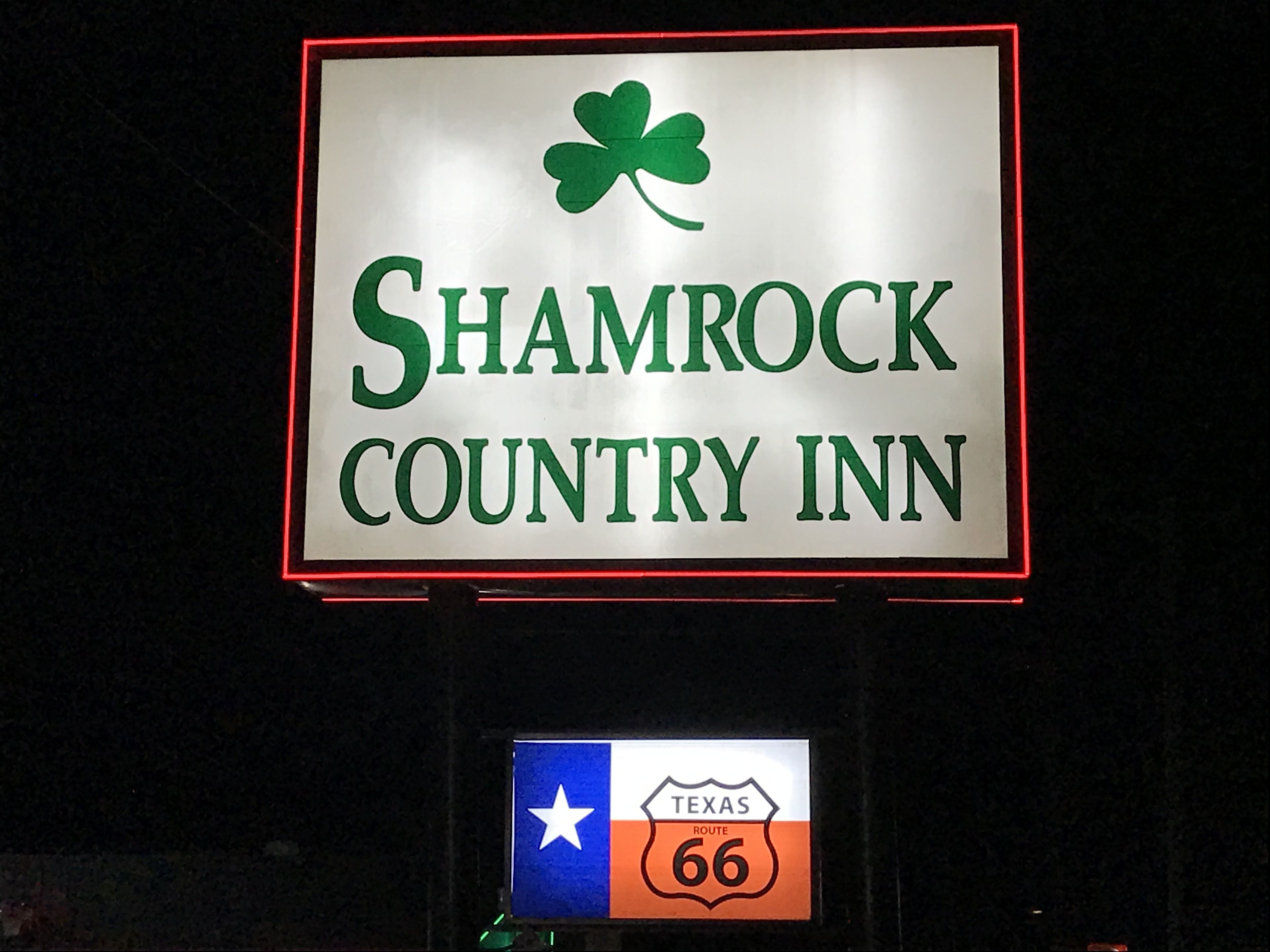 A sign for Shamrock Country Inn with a Texas Route 66 emblem below it.