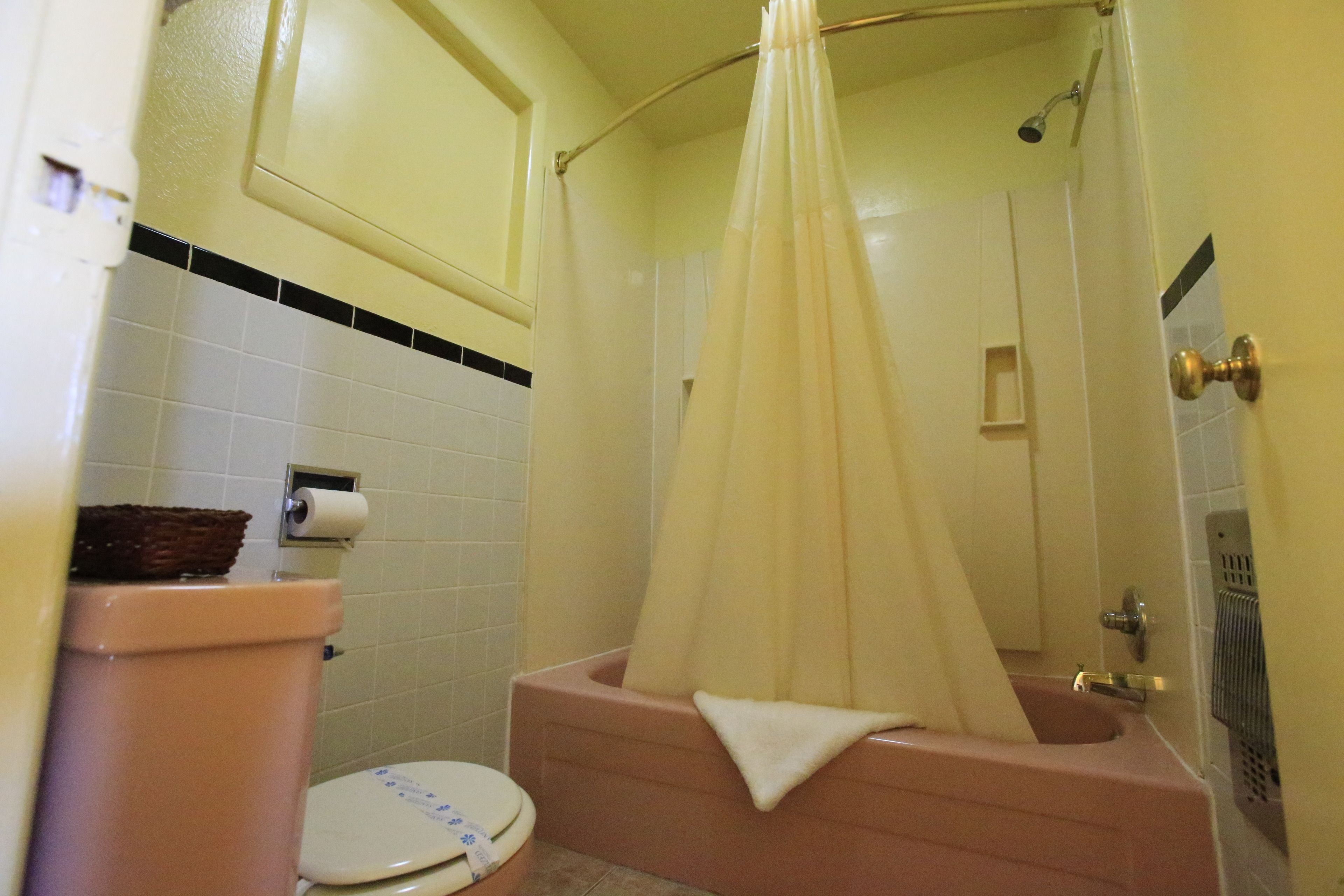 A bathroom with a toilet, a bathtub, and a shower curtain.