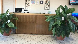 A reception desk with a laptop, framed certificates, and a clock on the wall. - Shamrock Country Inn (Shamrock)