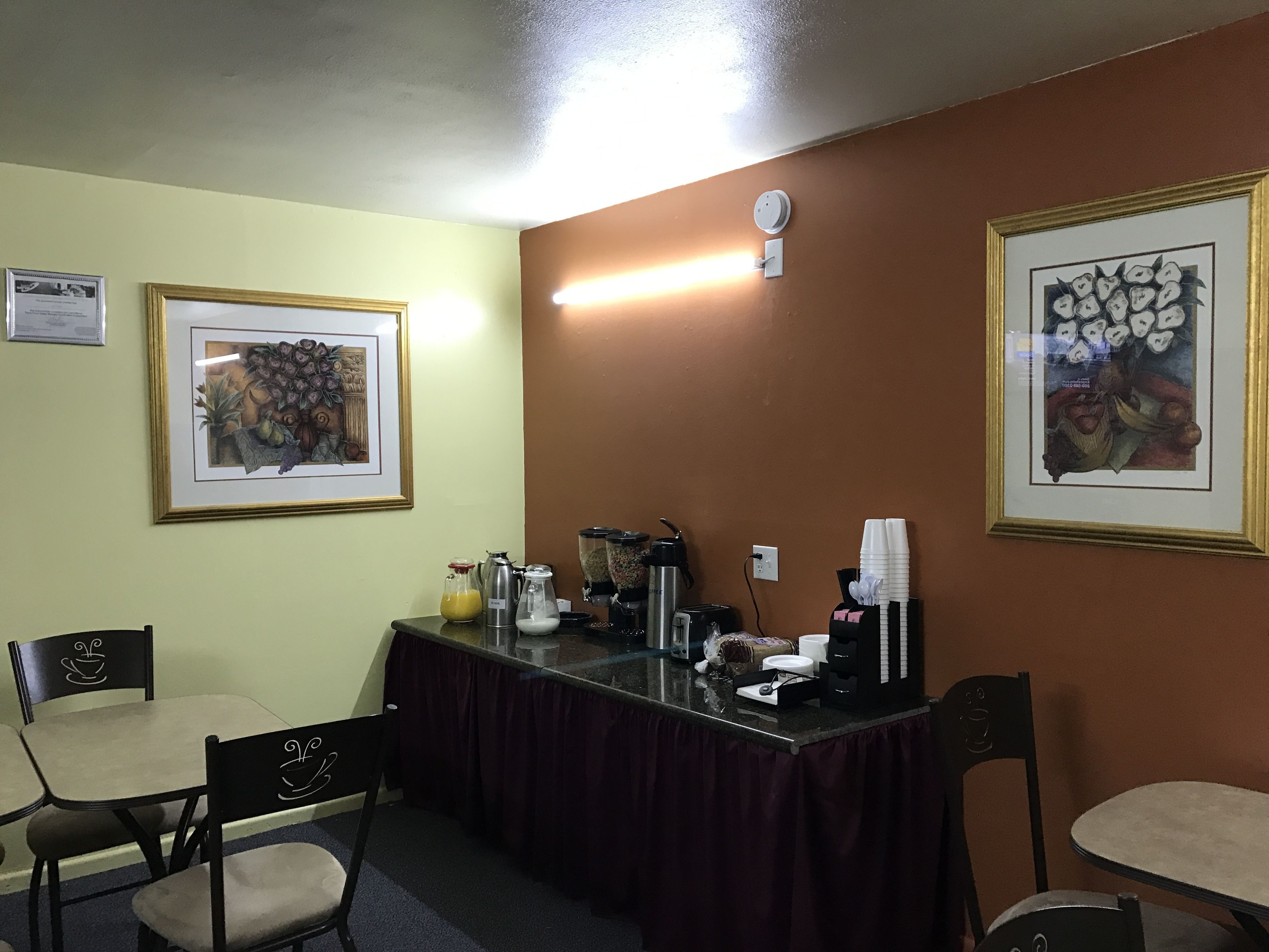 A conference room with a table, chairs, coffee-making equipment, and framed artwork on the walls.