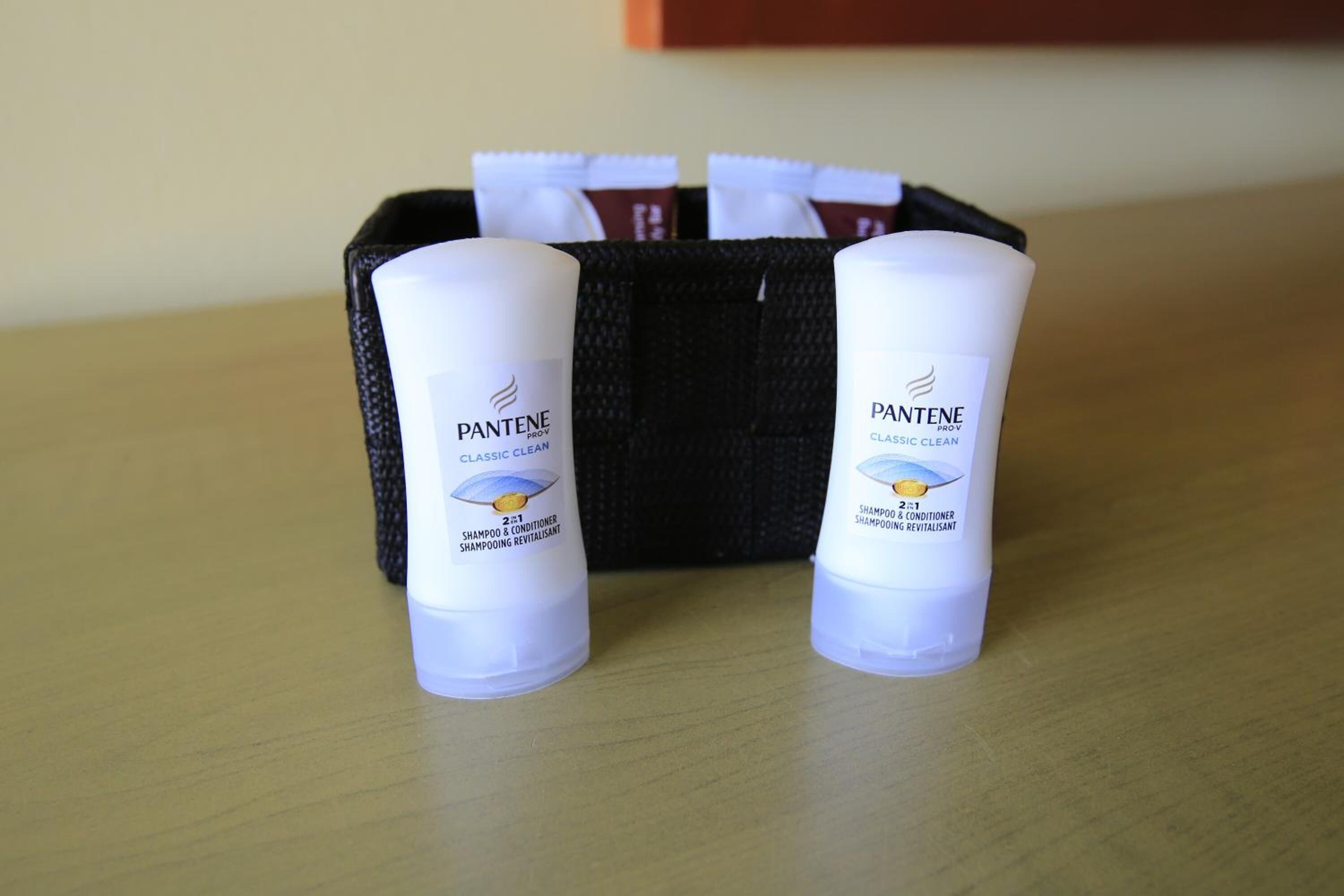Two Pantene Classic Clean shampoo and conditioner bottles on a wooden surface.