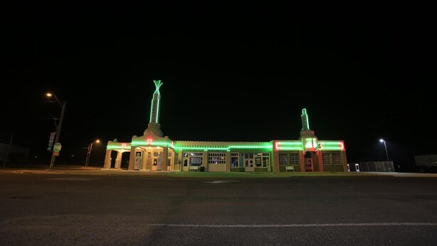 A building with a flat roof, a central entrance, and a small tower with a flagpole. - Shamrock Country Inn (Shamrock)