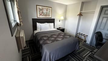 Una habitación de hotel con cama, mesita de noche, lámpara, silla y puerta.