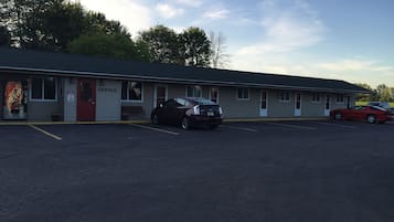 A motel with a Coca-Cola sign, a parking lot, and two cars parked in front.