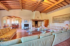 A spacious living room with a fireplace, sofas, and a dining area. - Villa Leonardo (Vinci)