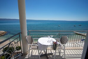 A table with chairs and a bottle of champagne on a balcony overlooking the sea.