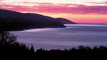 A coastal landscape with a calm sea and hills in the background.
