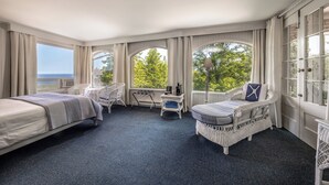 Une chambre d’hôtel avec deux lits, un bureau, une chaise et de grandes fenêtres avec des rideaux.