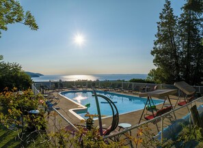 Una piscina con sillas de descanso y vista al mar.