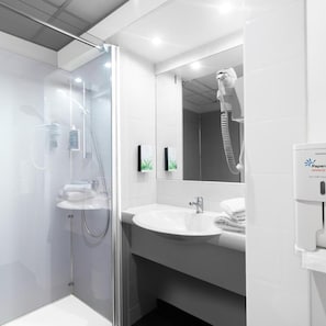 A modern bathroom with a glass-enclosed shower, a white sink, and a mirror. - Brit Hotel Montpellier Parc Expo (Perols)