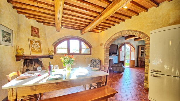 A rustic kitchen with a wooden table set for dining, a bench, and a refrigerator. - Casa Anna (Barberino Tavarnelle)