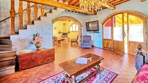 A spacious living area with a wooden staircase, a chandelier, a television, and a cozy seating arrangement. - Casa Anna (Barberino Tavarnelle)
