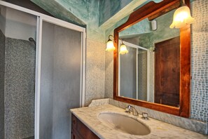 A bathroom with a marble sink, a wooden-framed mirror, and mosaic tile walls. - Casa Anna (Barberino Tavarnelle)