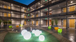 A modern hotel with multiple floors, a central atrium with artificial grass and illuminated spheres, and a variety of seating options. - Aventura Hotel (Los Angeles)