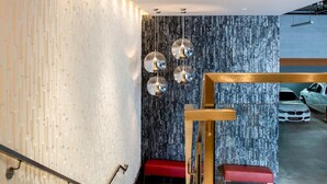 A modern interior with a wooden staircase, a red bench, and a wall with a textured pattern. - Aventura Hotel (Los Angeles)
