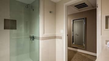 Un baño moderno con cabina de ducha de vidrio, puerta con espejo y suelo de baldosas.