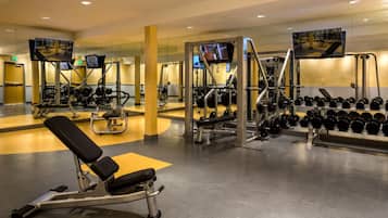 A modern gym with various exercise equipment, including weight machines, free weights, and cardio machines.