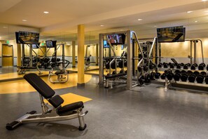 A modern gym with various exercise equipment, including weight machines, free weights, and cardio machines. - Aventura Hotel (Los Angeles)