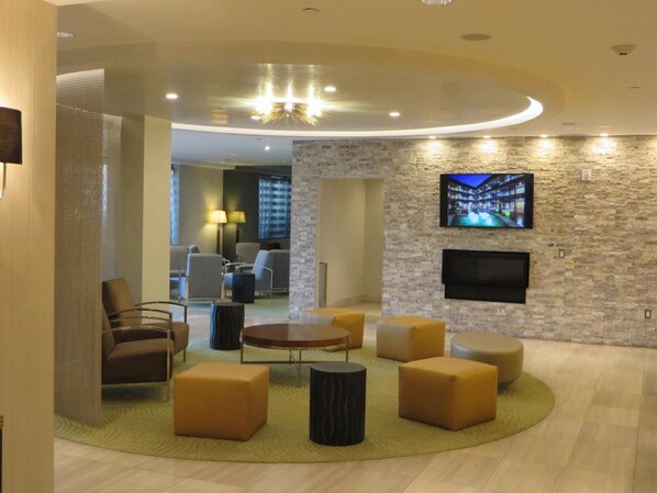 A modern living room with a stone accent wall, a flat-screen TV, and a round coffee table.