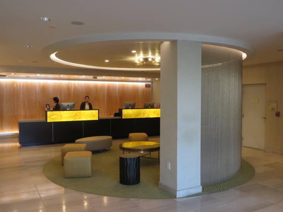 Un espace d’accueil moderne avec un comptoir incurvé, deux réceptionnistes et un coin salon comprenant des poufs et une table ronde.